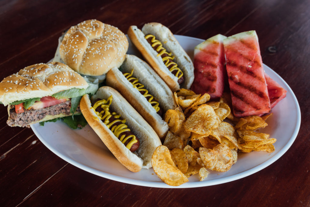 A classic hamburger and beef dogs bbq with grilled watermelon and bbq kettle chips.